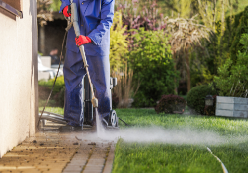 A worker power washing a backyard patio